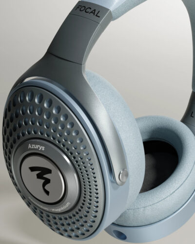 Over-ear light blue headphones close-up showing perforated ear cup and brand logo on the metallic plate.